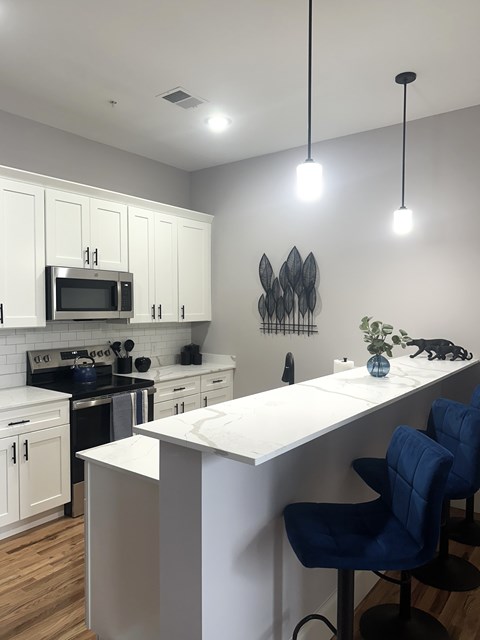A kitchen with a white counter and blue chairs.